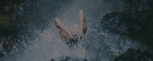 Person diving into water with a dark, forested background